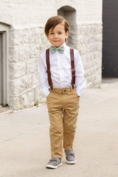 Boy wearing Armoniia brown leather suspenders and dusty sage bow tie